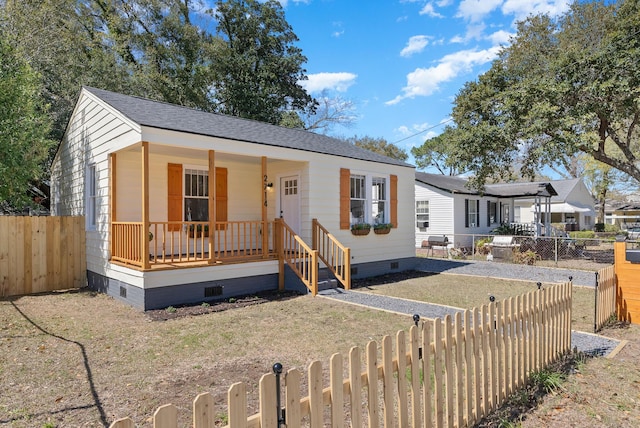 view of front of house featuring crawl space, roof with shingles, a porch, and a fenced front yard