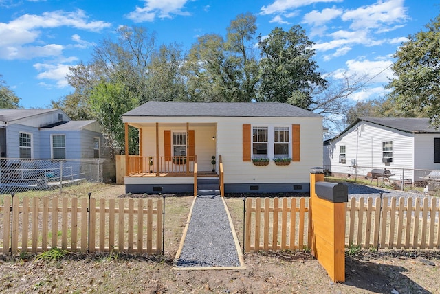 bungalow-style home featuring crawl space, roof with shingles, a porch, and a fenced front yard