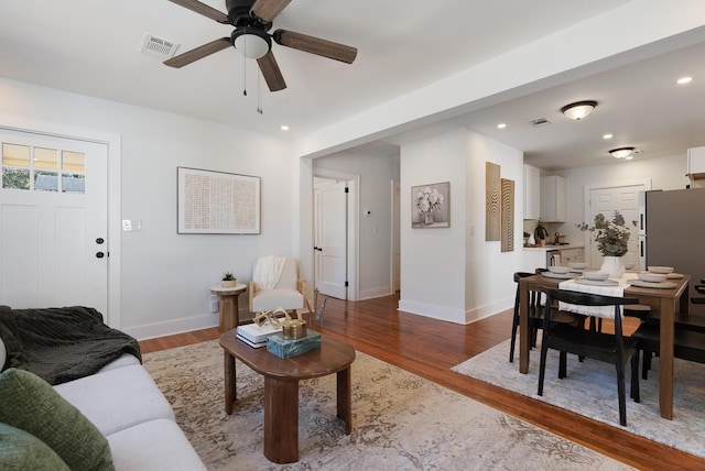 living area with recessed lighting, wood finished floors, visible vents, and baseboards