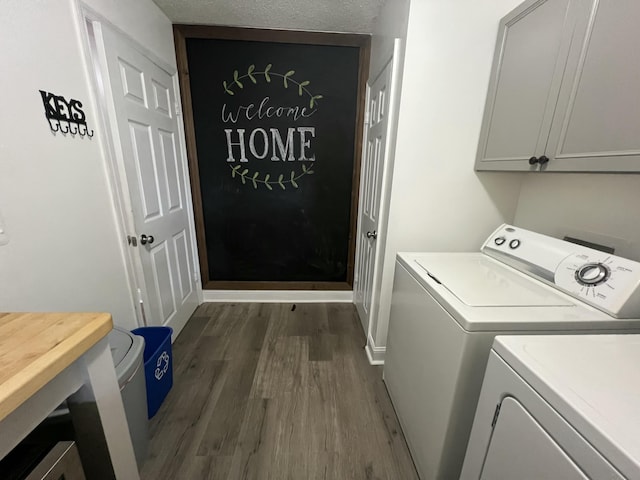 laundry room featuring baseboards, cabinet space, dark wood-type flooring, and washing machine and dryer