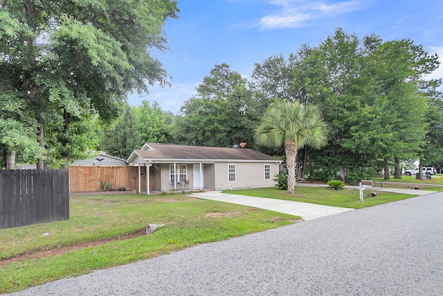 ranch-style home featuring a front yard, fence, covered porch, and driveway