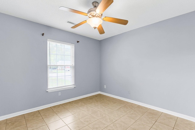 empty room featuring light tile patterned floors, baseboards, visible vents, and ceiling fan