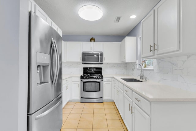 kitchen with visible vents, backsplash, white cabinets, stainless steel appliances, and a sink