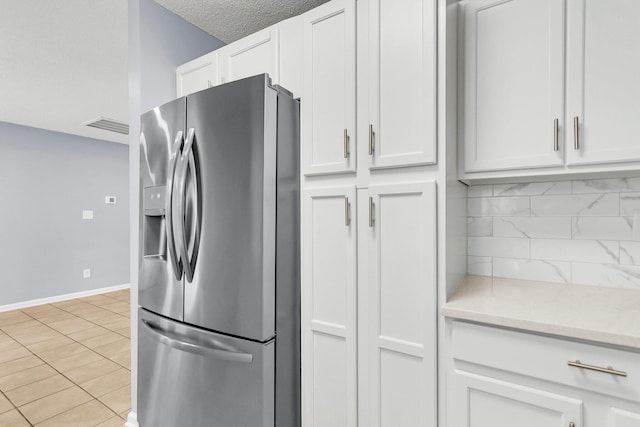 kitchen featuring backsplash, white cabinets, stainless steel fridge with ice dispenser, light tile patterned floors, and baseboards