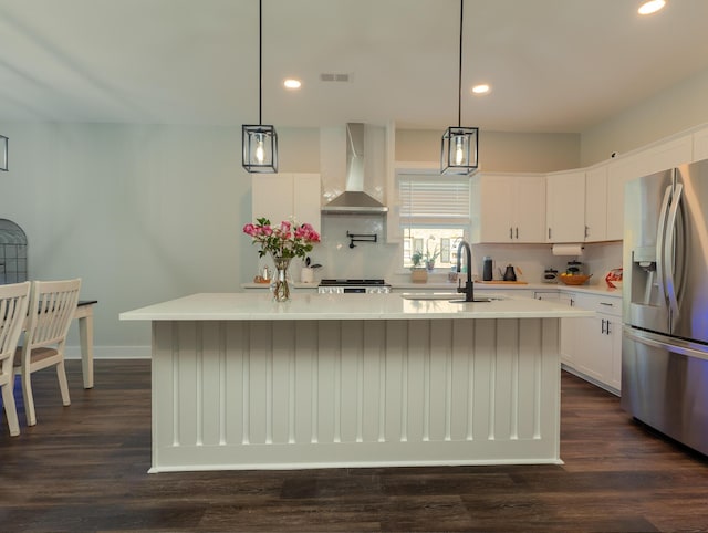 kitchen featuring sink, stainless steel fridge, an island with sink, and wall chimney exhaust hood