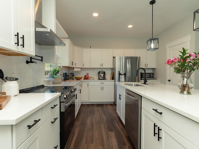 kitchen with appliances with stainless steel finishes, dark hardwood / wood-style flooring, wall chimney exhaust hood, white cabinetry, and backsplash