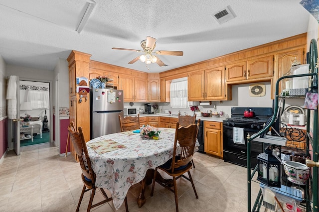 kitchen with a textured ceiling, black appliances, light countertops, and visible vents