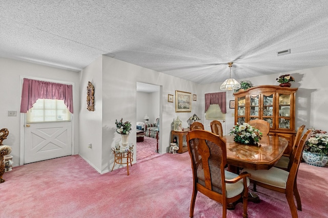 carpeted dining space featuring visible vents and a textured ceiling