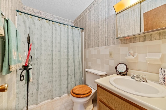 bathroom with wallpapered walls, toilet, tile patterned floors, a textured ceiling, and tile walls