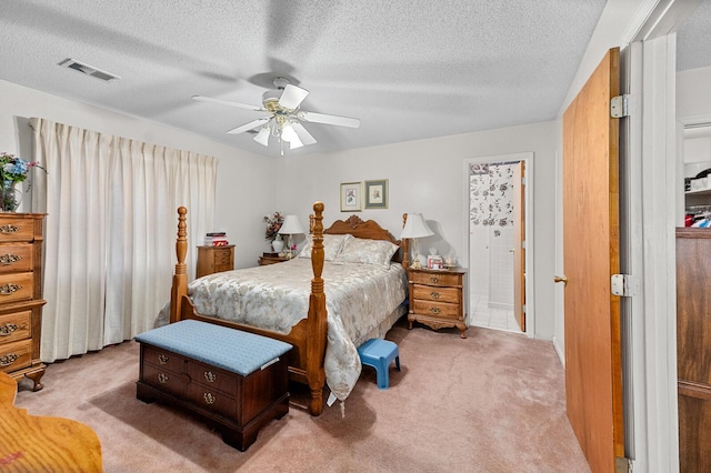 bedroom featuring a textured ceiling, ceiling fan, visible vents, and light colored carpet