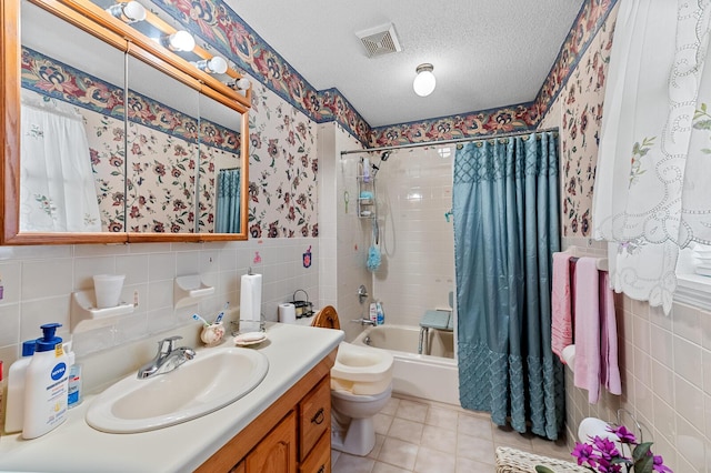 full bath featuring tile walls, visible vents, shower / bath combo, a textured ceiling, and vanity