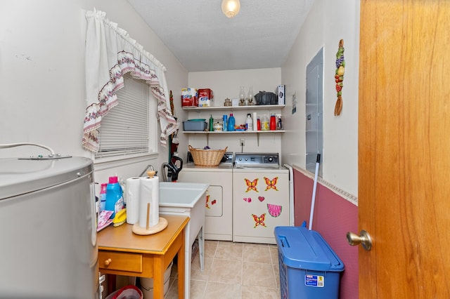 laundry area with laundry area, light tile patterned floors, washer and dryer, a textured ceiling, and water heater