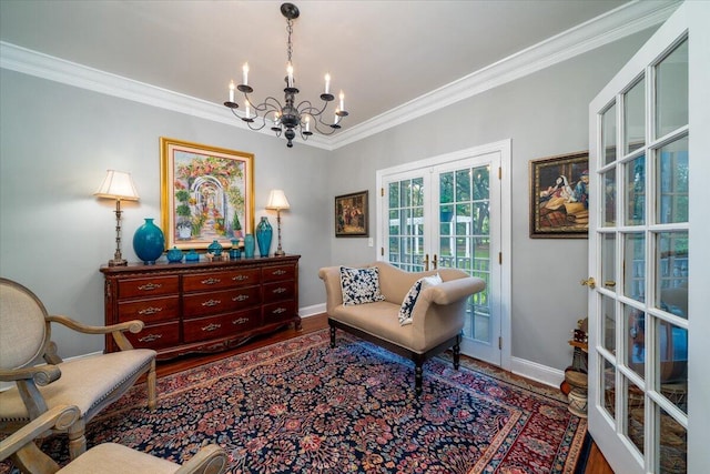 living area with hardwood / wood-style flooring, french doors, crown molding, and a chandelier