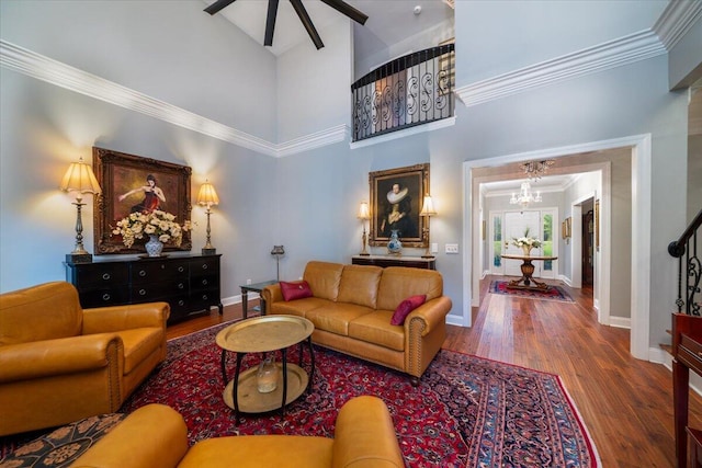 living room with ornamental molding, a chandelier, a high ceiling, and wood-type flooring