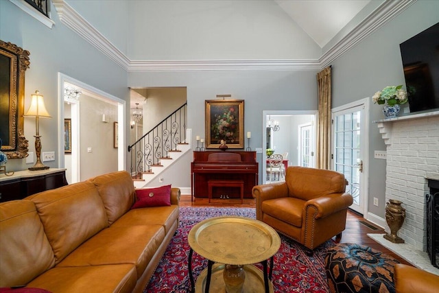 living room with a brick fireplace, hardwood / wood-style floors, and a high ceiling