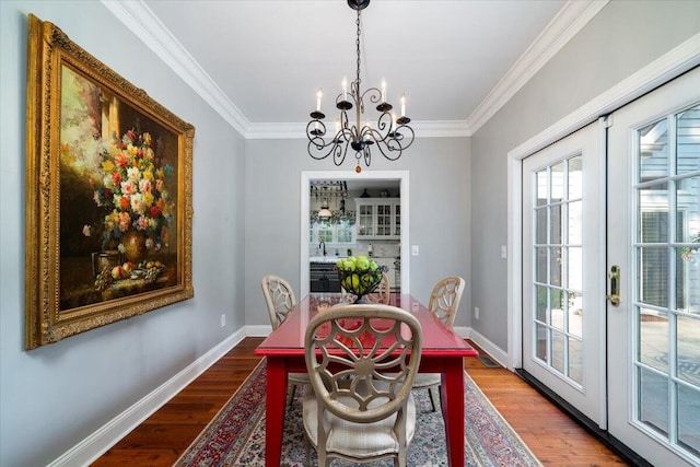 dining space with hardwood / wood-style flooring, crown molding, and an inviting chandelier