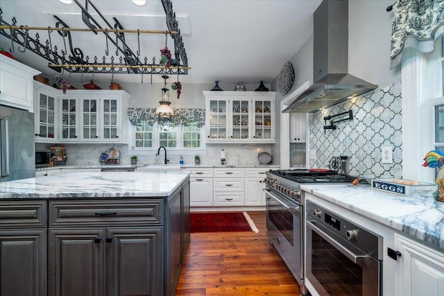 kitchen with wall chimney exhaust hood, decorative backsplash, dark hardwood / wood-style floors, stainless steel appliances, and white cabinets