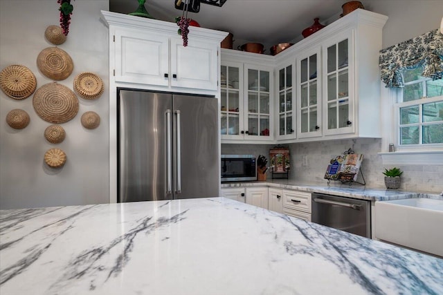 kitchen featuring appliances with stainless steel finishes, decorative backsplash, light stone countertops, and white cabinets