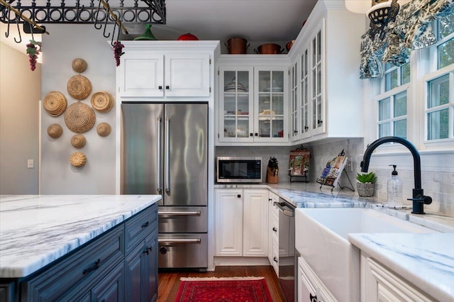 kitchen with backsplash, appliances with stainless steel finishes, sink, dark wood-type flooring, and blue cabinets