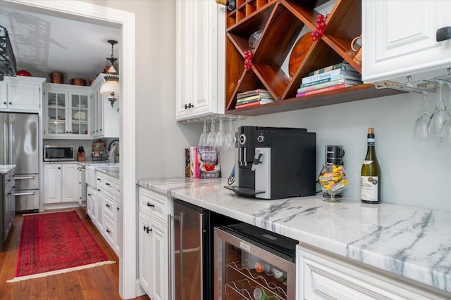 kitchen featuring hardwood / wood-style floors, light stone countertops, beverage cooler, stainless steel appliances, and white cabinets