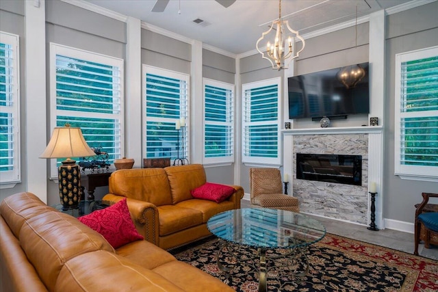 living room featuring ceiling fan with notable chandelier, a fireplace, crown molding, and a healthy amount of sunlight