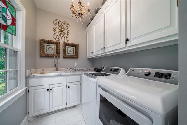 clothes washing area with sink, light tile patterned floors, a chandelier, cabinets, and washer and dryer