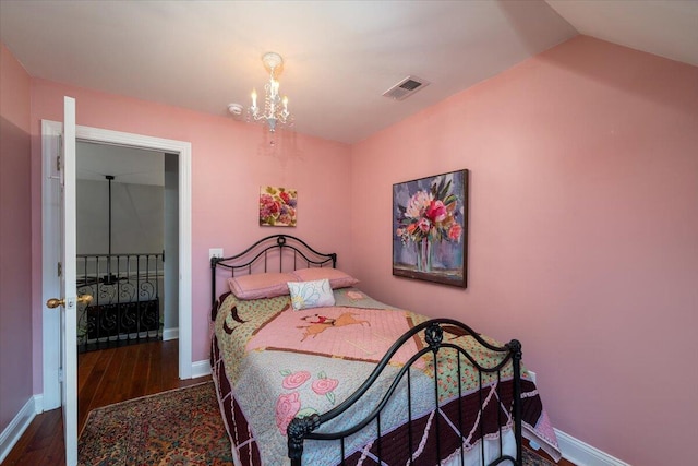 bedroom with vaulted ceiling, wood-type flooring, and an inviting chandelier