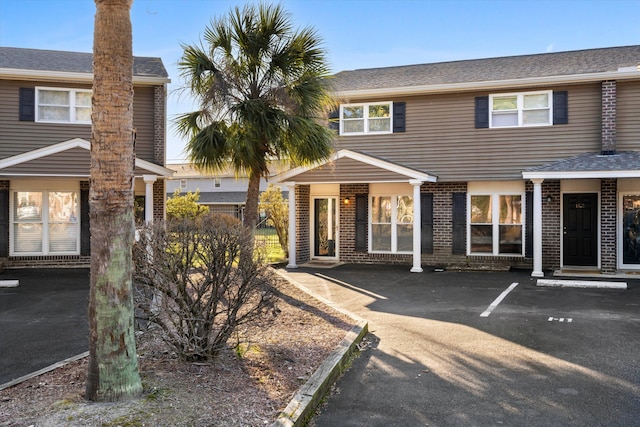 view of exterior entry featuring uncovered parking and brick siding