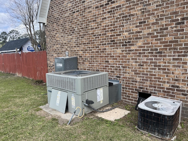 exterior details featuring fence, central AC unit, and brick siding