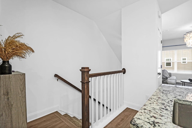 stairway with hardwood / wood-style floors and an inviting chandelier