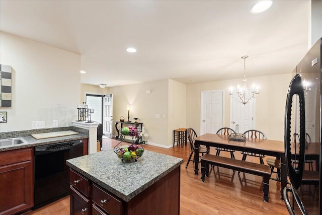 kitchen with dark countertops, a notable chandelier, light wood-type flooring, and black dishwasher
