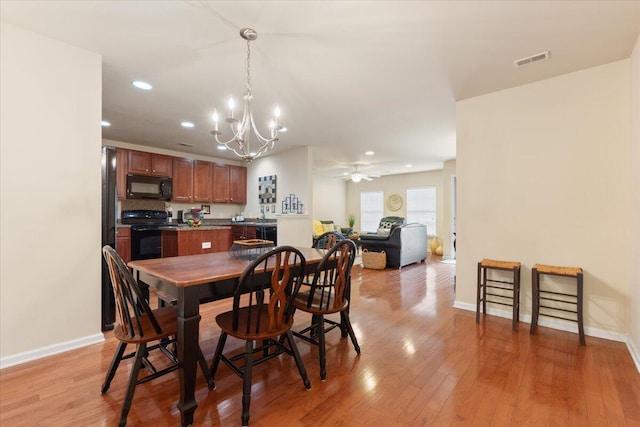 dining area with ceiling fan with notable chandelier, visible vents, baseboards, light wood-style floors, and recessed lighting