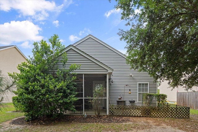 rear view of house with a sunroom and fence