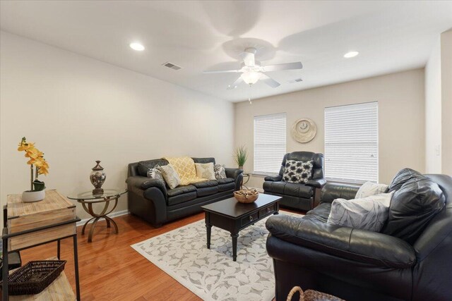 living area featuring baseboards, a ceiling fan, visible vents, and light wood-style floors