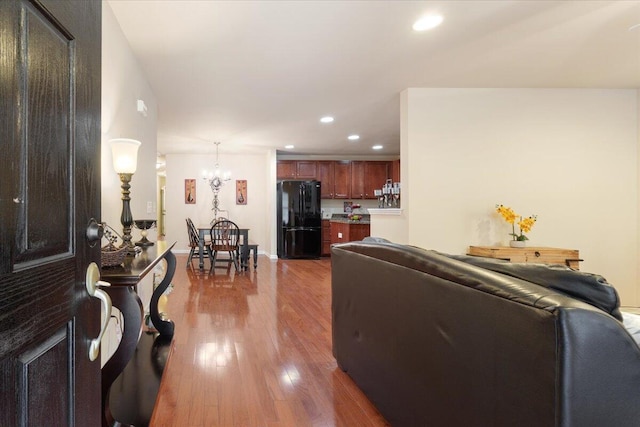 living room with recessed lighting, wood finished floors, baseboards, and a notable chandelier