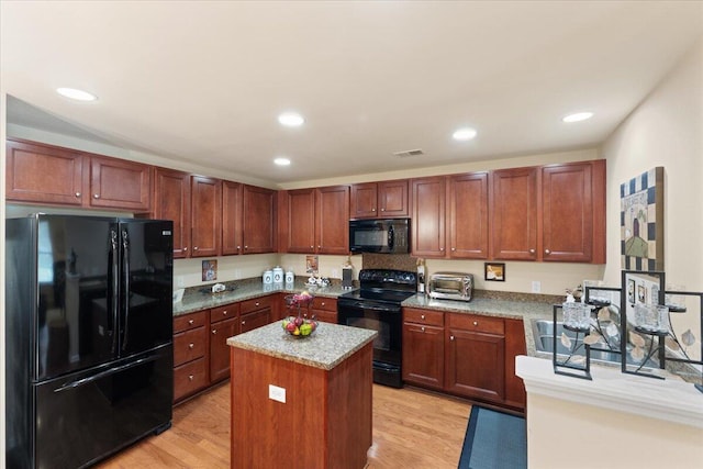 kitchen featuring black appliances, recessed lighting, visible vents, and a kitchen island