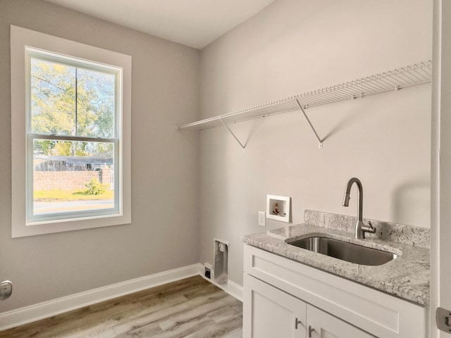 laundry room with cabinets, light hardwood / wood-style flooring, washer hookup, and sink