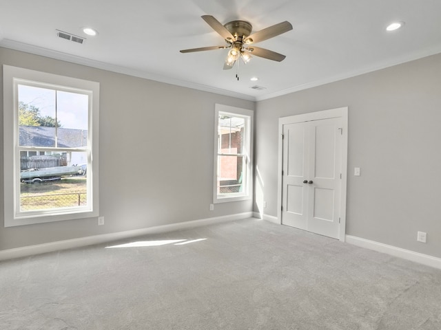 carpeted spare room with ornamental molding, a wealth of natural light, and ceiling fan