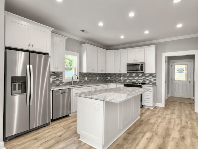 kitchen with stainless steel appliances, a kitchen island, light wood-type flooring, sink, and white cabinets