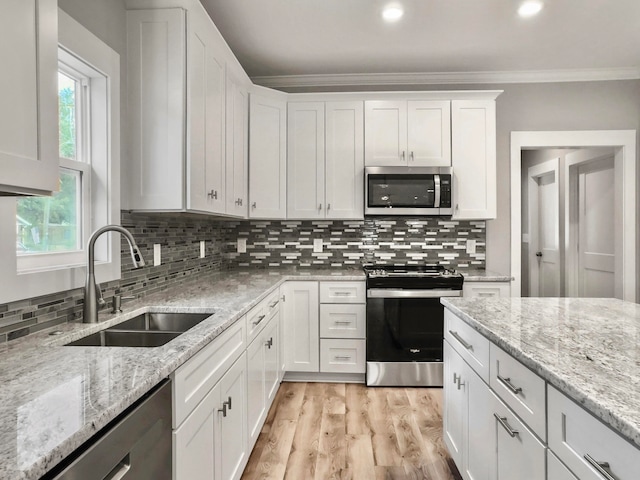 kitchen with white cabinets, sink, ornamental molding, backsplash, and appliances with stainless steel finishes