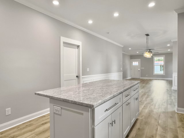 kitchen featuring light hardwood / wood-style floors, a center island, ceiling fan, crown molding, and white cabinetry