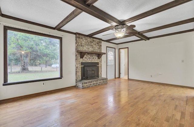 unfurnished living room with light wood-type flooring, a textured ceiling, ceiling fan, beam ceiling, and a fireplace