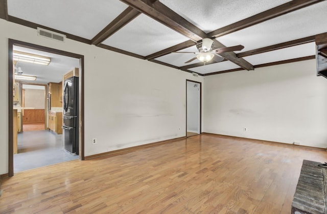 spare room with beam ceiling, light wood-type flooring, a textured ceiling, and ceiling fan