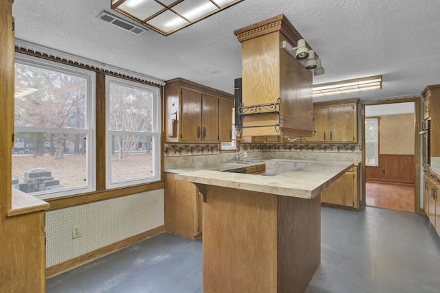 kitchen featuring wooden counters, a textured ceiling, a healthy amount of sunlight, and wood walls