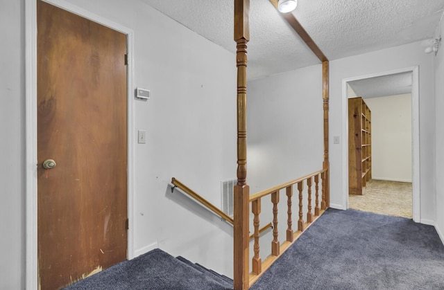 staircase featuring carpet and a textured ceiling