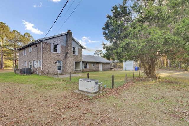 view of side of property featuring central AC unit and a yard