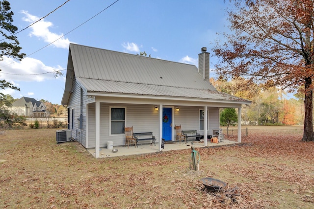 rear view of property with central AC unit, a patio area, and a lawn