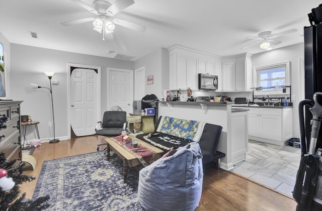 living room with ceiling fan, sink, and wood-type flooring