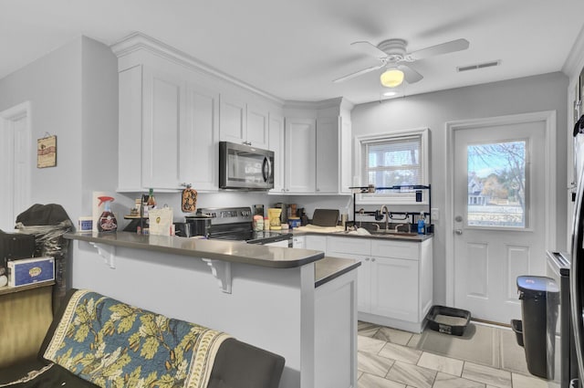 kitchen with a kitchen bar, electric range, kitchen peninsula, and white cabinetry