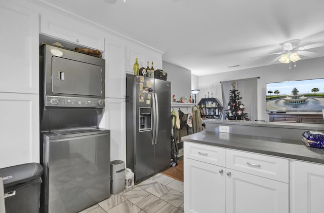 kitchen featuring stainless steel fridge, white cabinets, stacked washer / drying machine, and ceiling fan